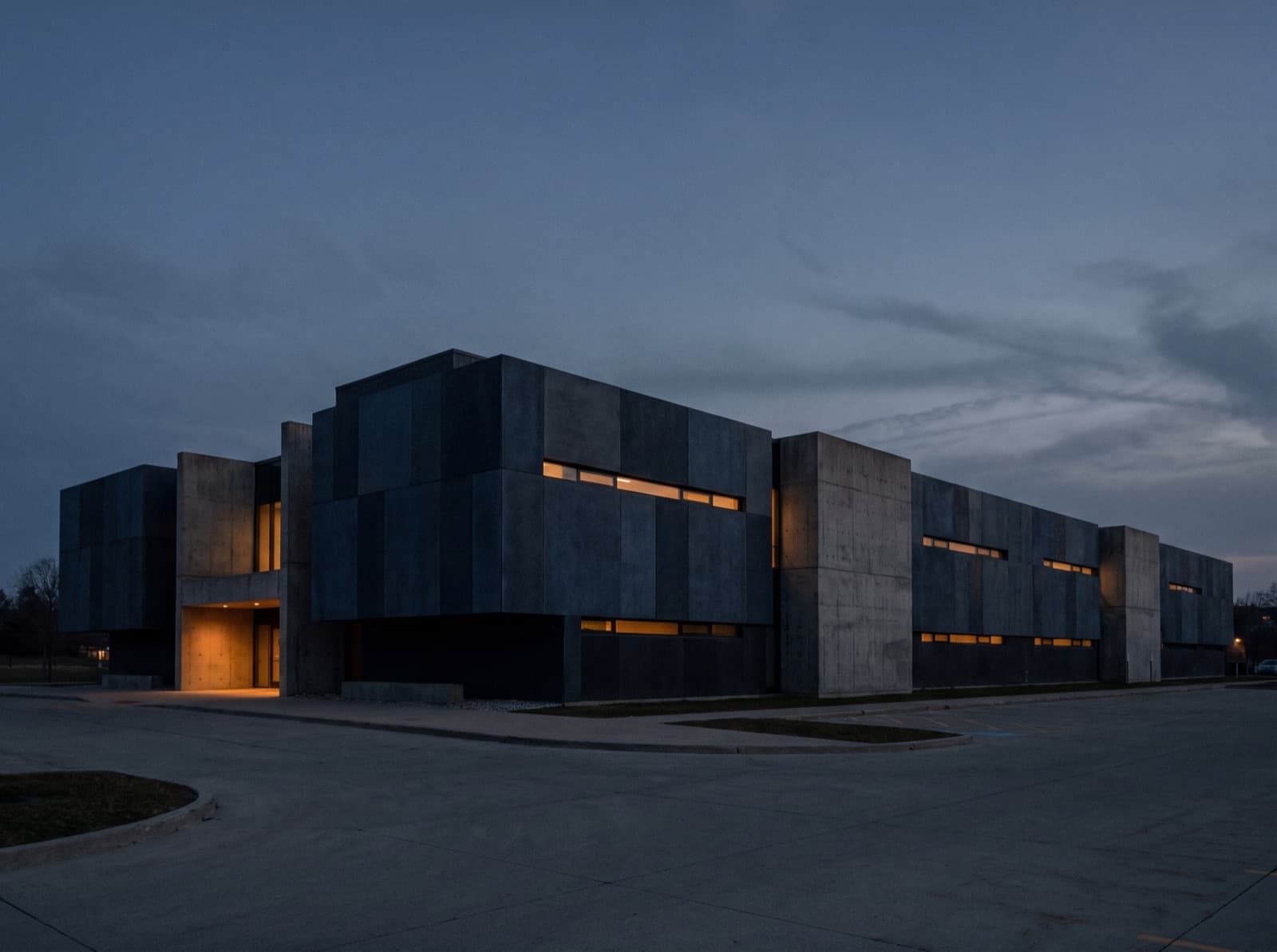 Low concrete special-purpose facility at dusk with narrow slot windows